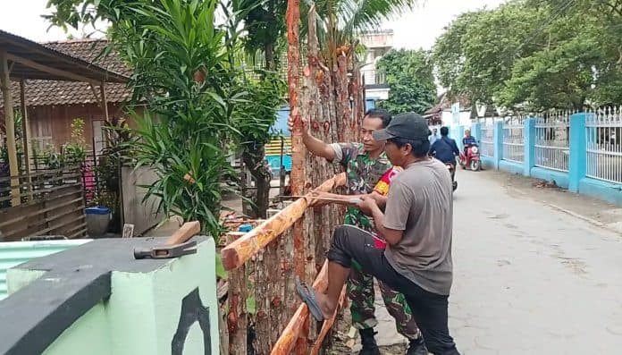 Babinsa Sapeken Gotong Royong Bantu Bangun Pagar Rumah Warga, Perkuat Kemanunggalan TNI dan Masyarakat